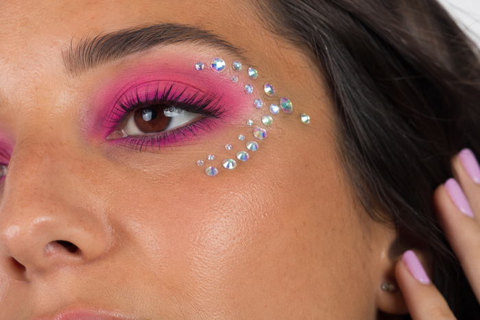 Close-up of a person with pink eye makeup and face jewels.